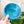 Hand holding a blue geometric-patterned object with plants in the background