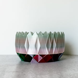 Geometric multicolored vase on a light surface with a white background